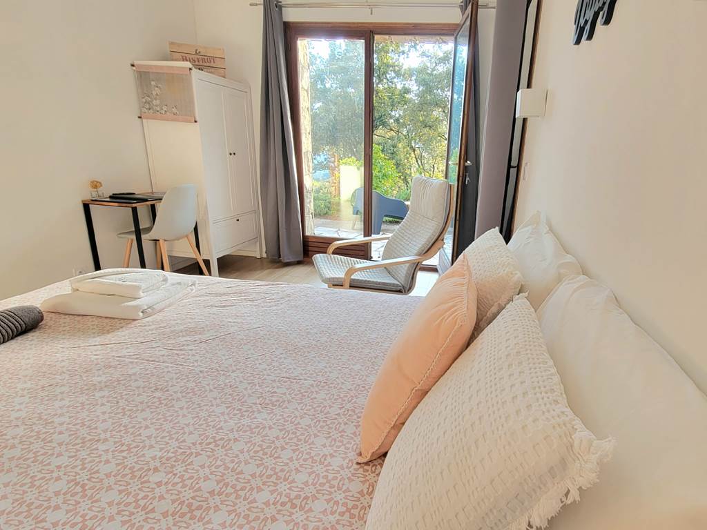 Intérieur d'une chambre d'hôtes décorée avec goût offrant une vue dégagée sur le jardin.