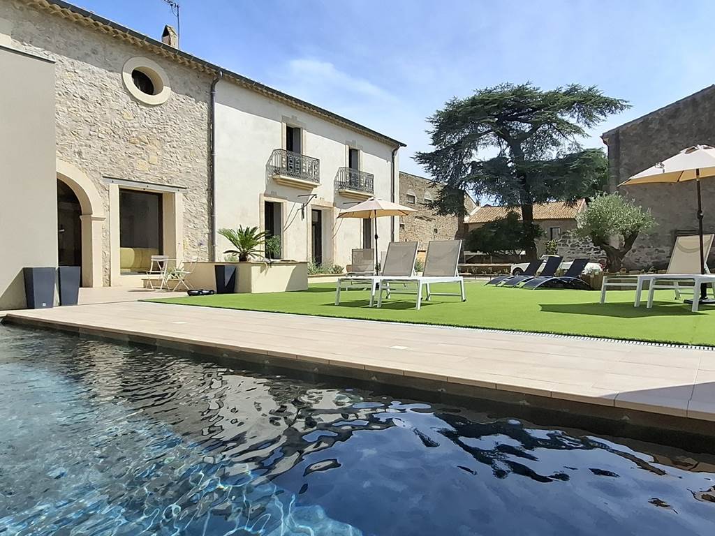 Vue d’ensemble des Gîtes de Monte Blanco avec la piscine et les façades rénovées, près de Pézenas.