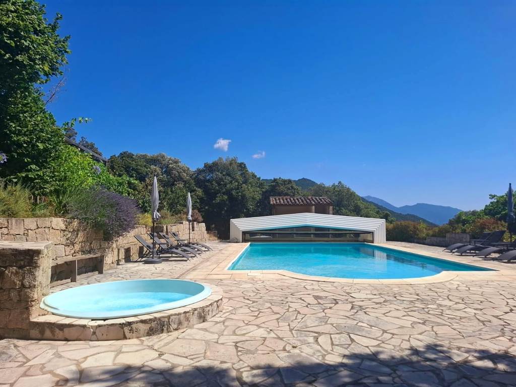 Grande piscine extérieure et jacuzzi avec vue panoramique sur les montagnes corses.