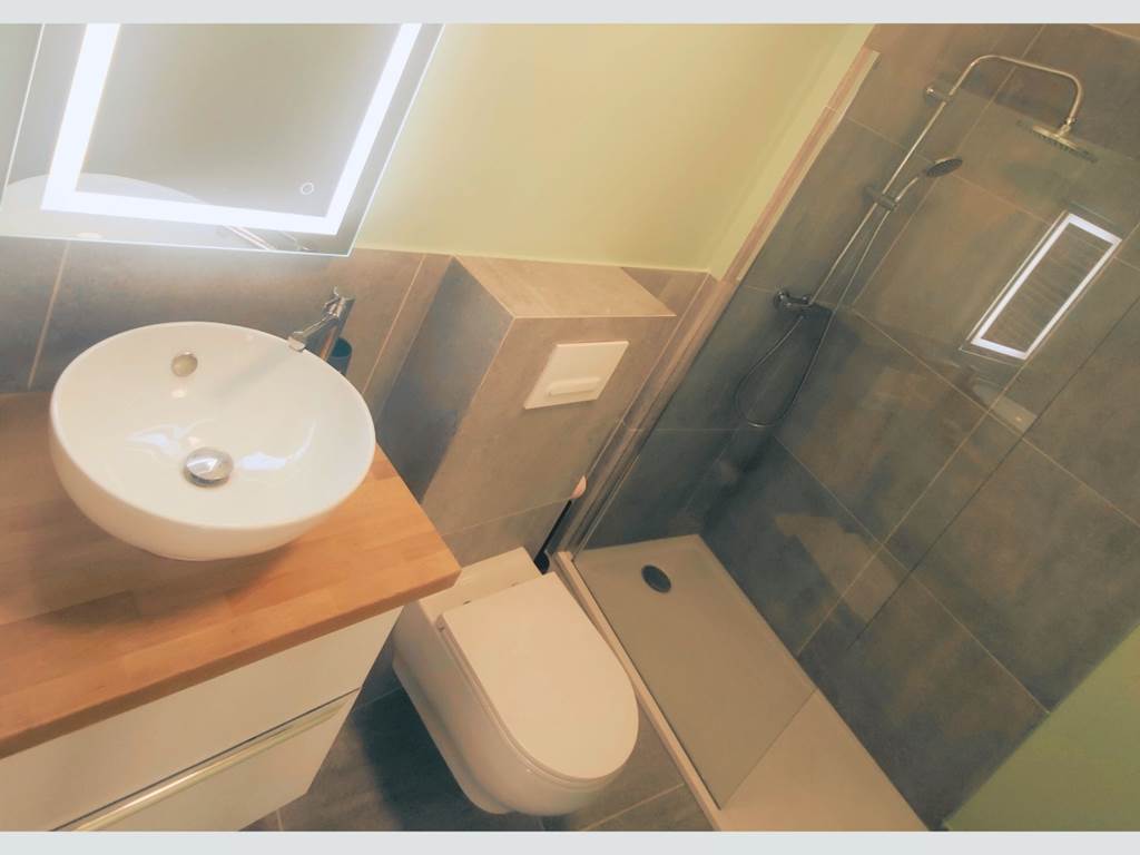 Salle d’eau contemporaine dans un esprit épuré Miroir rétroéclairé, vasque élégante et douche italienne : un espace bien pensé pour votre confort quotidien