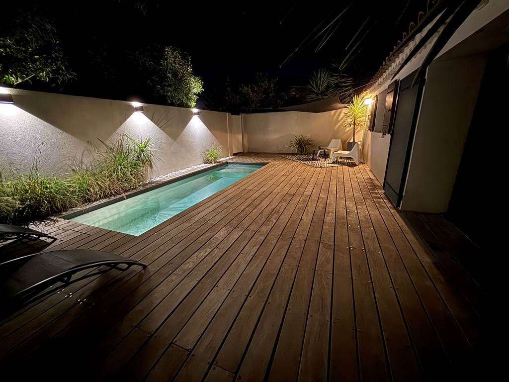 Ambiance magique autour de la piscine éclairée en soirée