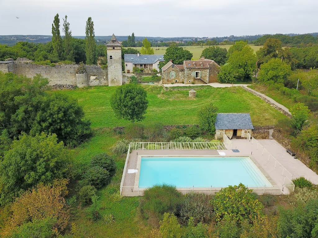Maisons XVIIIe avec piscine et ruines d’un château médiéval en arrière-plan.