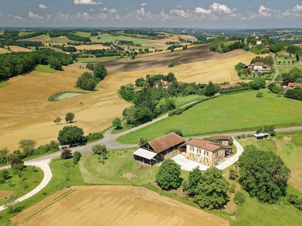 GITE LE GUITOU ET LE VILLAGE DE MONLEZUN AU LOIN LA PLAINE DE MARCIAC ET SON CLOCHER
