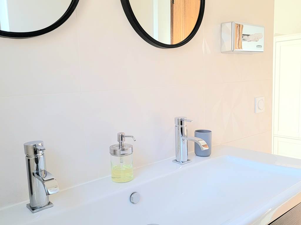 Salle de bain moderne et épurée avec double vasque, équipements de qualité au domaine.