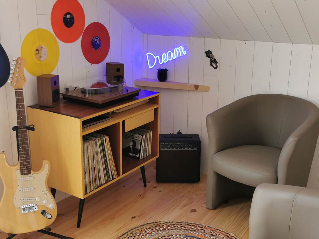 Espace musical coloré avec vinyles et guitares, parfait pour des loisirs créatifs et relaxation au Lodge de Kerescar à Plouarzel