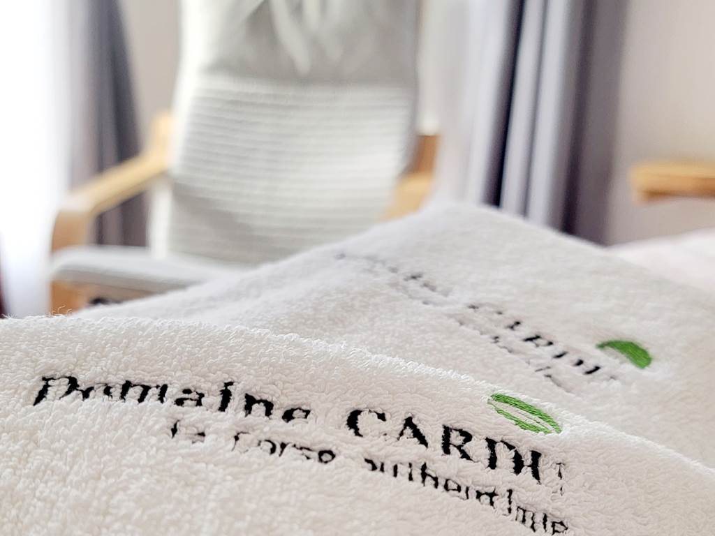 Linge de lit brodé au nom du Domaine Cardu pour un séjour confortable en Corse.