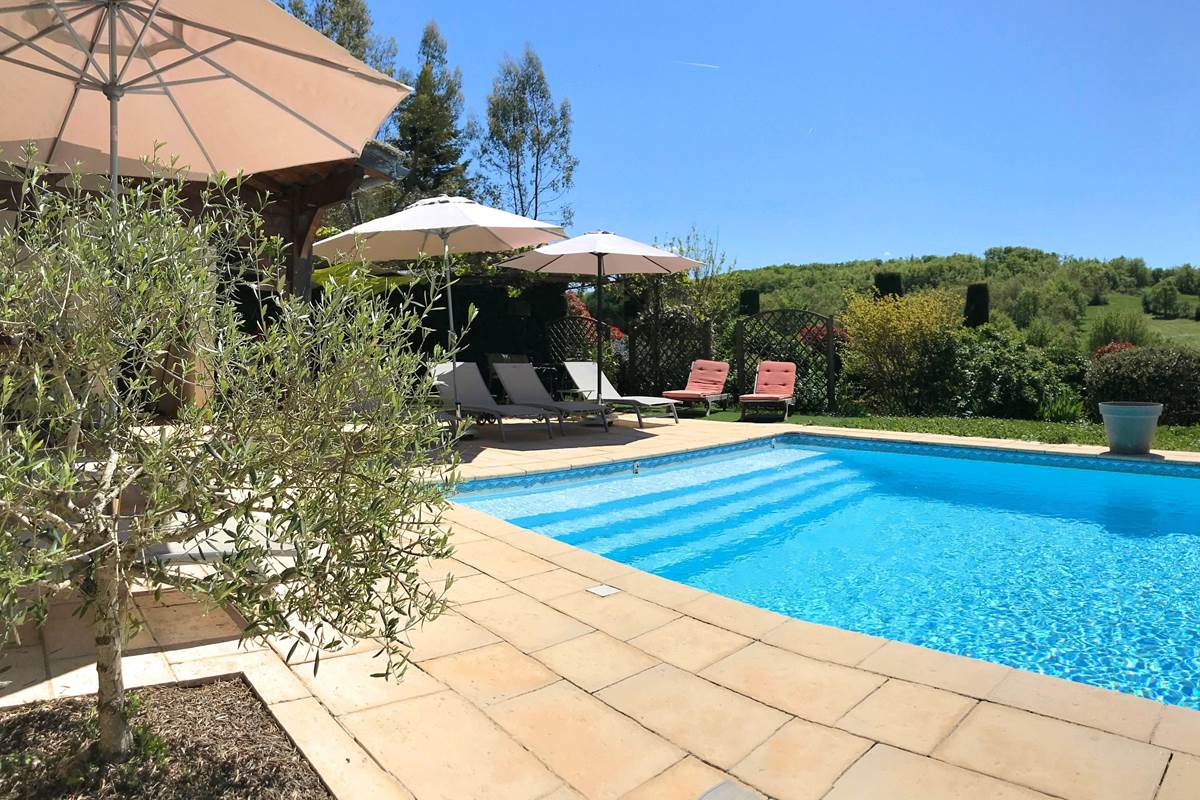 Espace piscine avec grandes plages, bains de soleil et parasols