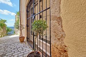 L’entrée se fait par une charmante porte-fenêtre, protégée par une grille en fer forgé typiquement provençale, ouvrant directement sur un petit sentier.