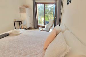Intérieur d'une chambre d'hôtes décorée avec goût offrant une vue dégagée sur le jardin.