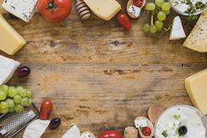 plateau-de-fromages-avec-tomates-raisins-et-mini-sandwichs-sur-un-bureau-en-bois-avec-espace-pour-ecrire-le-texte-min