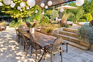"La grande table de l'orangerie, à l'ombre de la pergola, entre jardin et piscine"