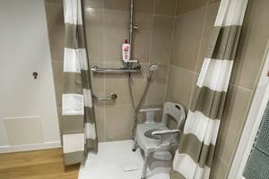 Douche à l'italienne avec barre de maintien et chaise à disposition