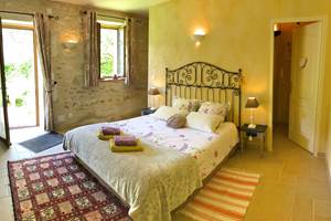 Chambre avec lit queen size, murs en pierre et peints à la chaux