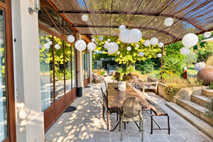 "la terrasse de la suite de l'Orangerie, à l'ombre des lanternes et ouverte sur le jardin"