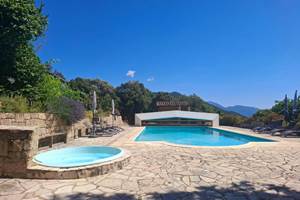 Grande piscine extérieure et jacuzzi avec vue panoramique sur les montagnes corses.