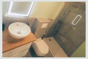 Salle d’eau contemporaine dans un esprit épuré Miroir rétroéclairé, vasque élégante et douche italienne : un espace bien pensé pour votre confort quotidien