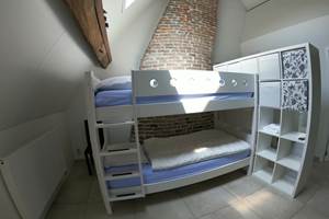 Chambre avec lits superposés séparée par des tentures et une étagère