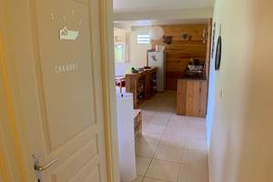 Vue du couloir vers le séjour avec porte de la chambre