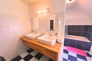 La salle de bain, baignoire, double lavabo et wc de la chambre Fuschia