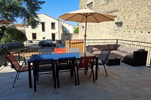 Terrasse du gîte Le Pressoir à Montblanc avec table à manger, barbecue et vue sur le domaine.