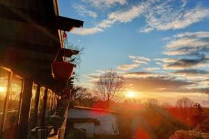 Le soleil couchant joue à -ric hochet- sur les baies vitrées de la salle à manger panoramique de notre Maison d'hôtes Le Ranch des Lacs