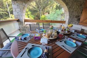 Table d'hôtes de charme dressée sur la terrasse en pierre pour un petit-déjeuner convivial en Corse.