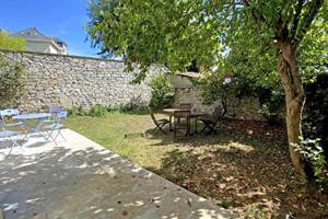 Terrasse du gîte avec tables extérieures et verdue