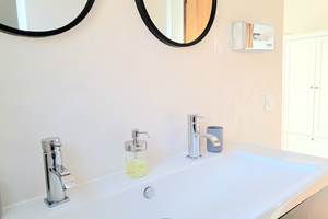 Salle de bain moderne et épurée avec double vasque, équipements de qualité au domaine.