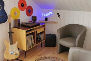 Espace musical coloré avec vinyles et guitares, parfait pour des loisirs créatifs et relaxation au Lodge de Kerescar à Plouarzel