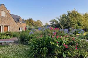 Maison entourée de massifs de fleurs (roses et agapenthes ici)