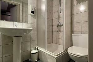 Salle de bain privative de la Chambre Double 3 comprenant une douche, un lavabo, un sèche cheveux et une toilette.