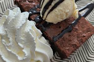 Dessert gourmand avec brownie au chocolat, glace vanille et chantilly servi à la table d'hôtes de La Girouardière.