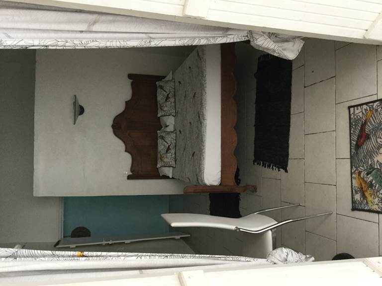 Notre plus petite chambre avec son lit baldequin, armoire, bureau, salle d’eau avec douche ,lave main et toilette, cuisine équipée sur terrasse, fresque d peint au fond sur brise vue.
